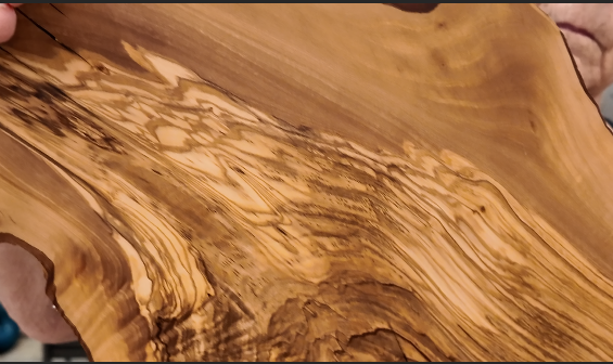 Detailed view of the natural olive wood grain and organic markings on the gathering board.
